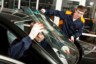A local auto glass repair company installs a replacement new car windshield.
